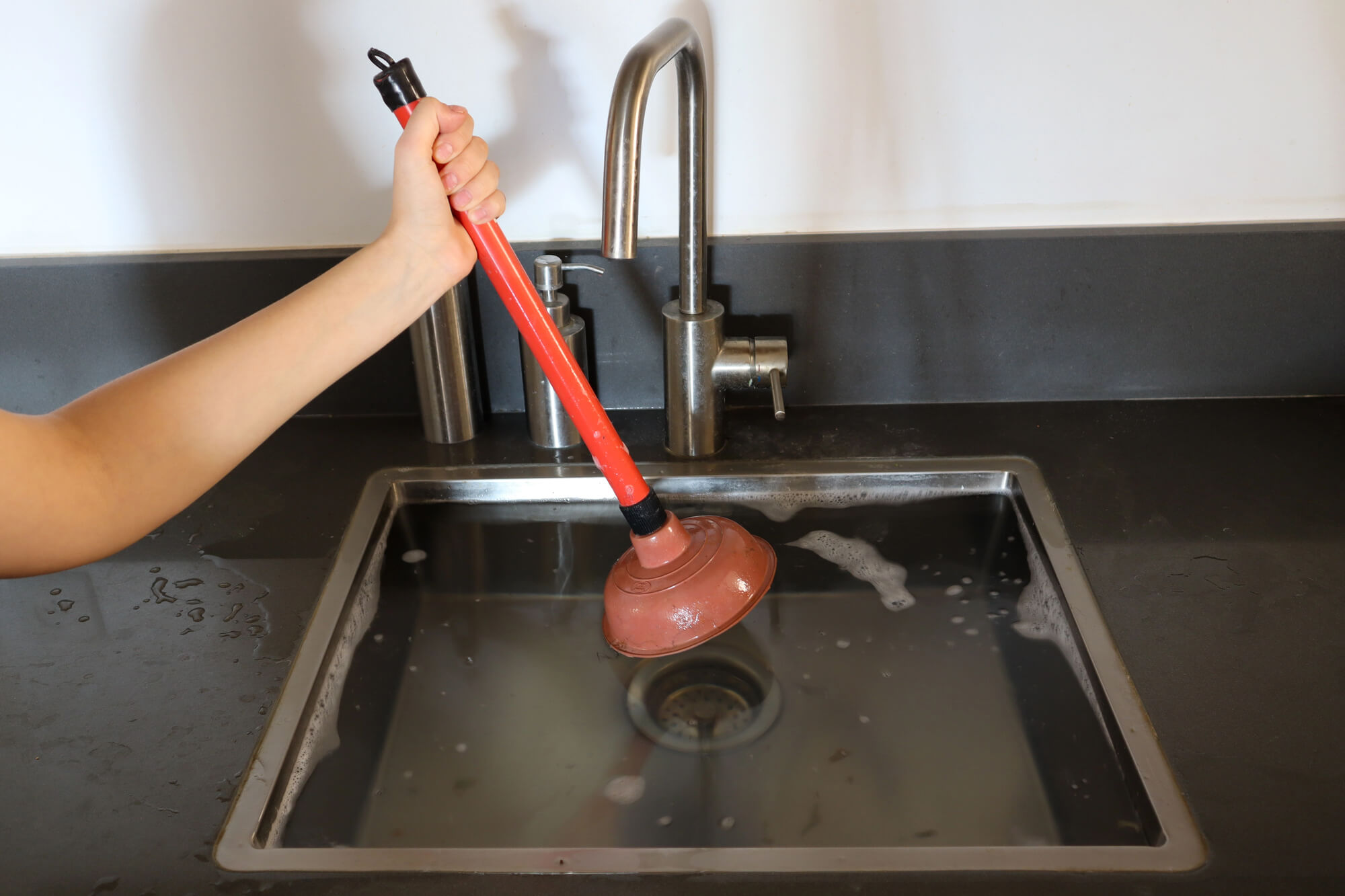 person-using-plunger-to-fix-clogged-drain-in-seattle