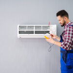 worker checking AC as part of HVAC Services in Seattle