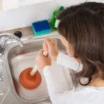 woman attempting to Fix clogged drain Seattle